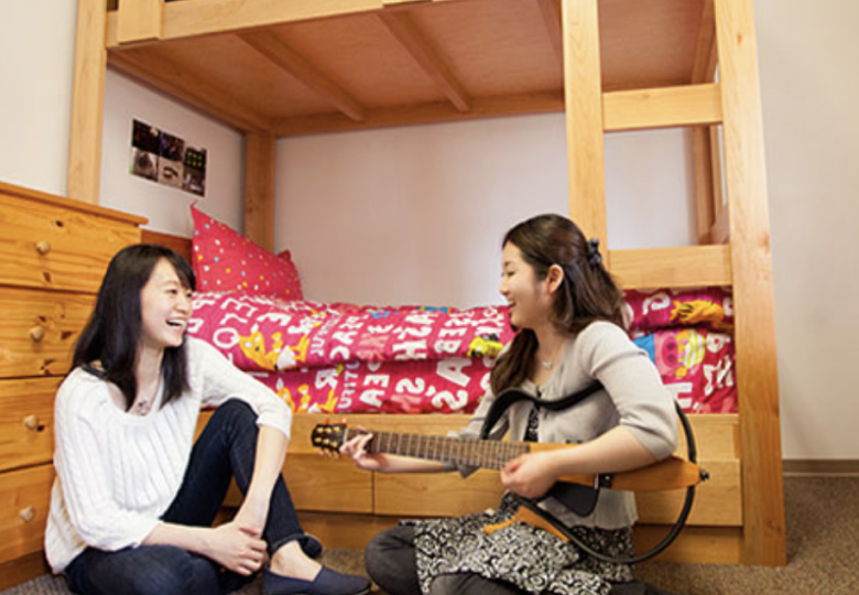 students in dorm room playing guitar