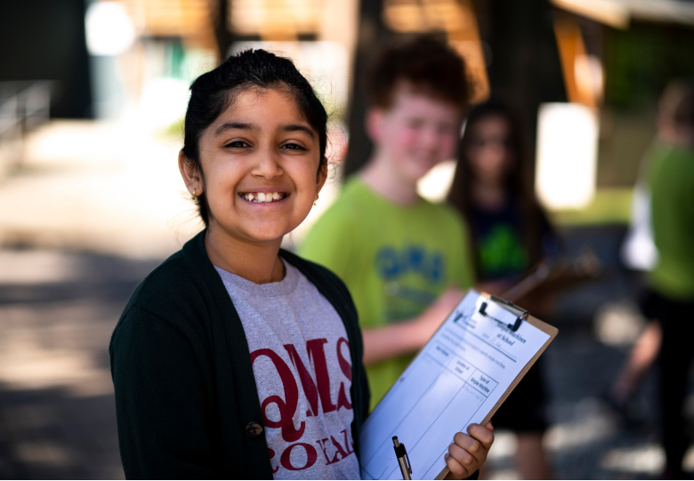 student holding checklist smiling